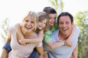 Couple giving two young children piggyback rides smiling